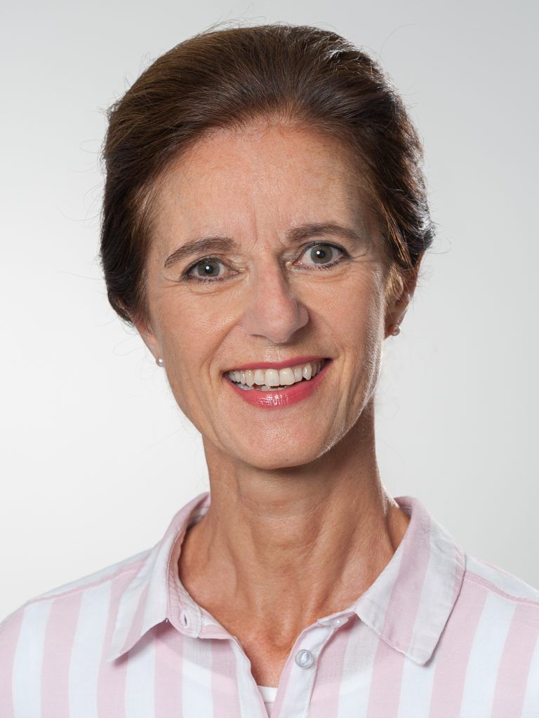 Porträt von Dr. med. Claudia Ertl, lächelnd in einem rosa gestreiften Hemd