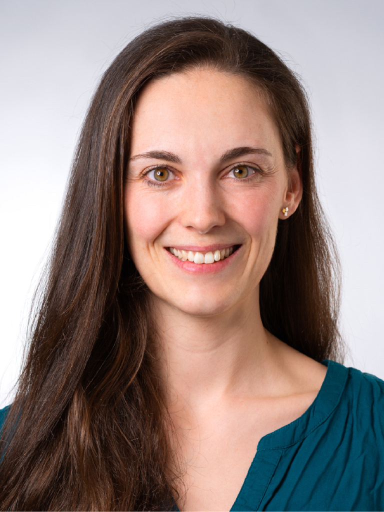 Porträt von Dr. med. Elisabeth Schuler-Hötscher, lächelnd mit langen dunklen Haaren in einem grünen Oberteil
