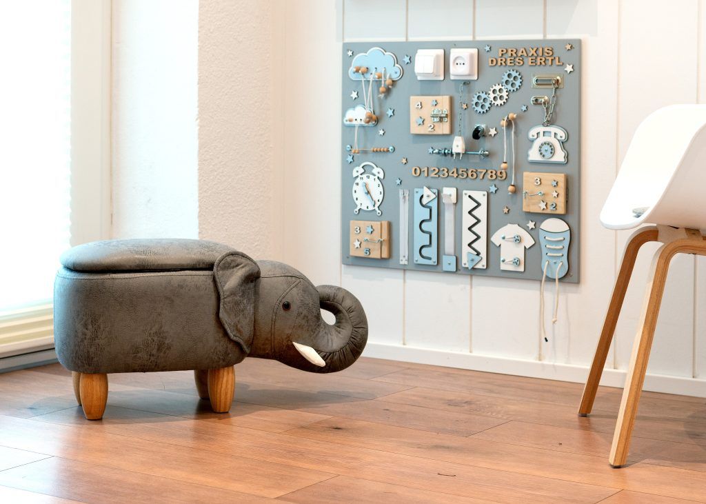 Spielecke für Kinder mit einem Elefantenhocker und einem Motorikboard an der Wand