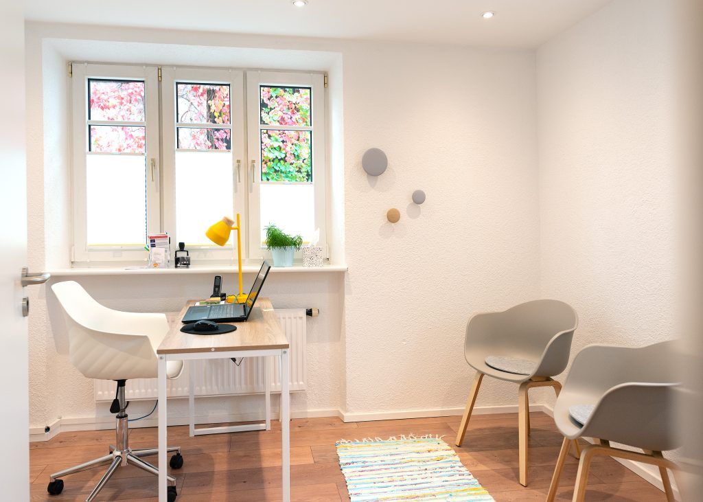 Einladendes Sprechzimmer mit Schreibtisch und Patientenstühlen