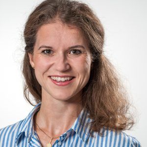 Porträt von Dr. med. Katharina Ertl, lächelnd in einem blau-weiß gestreiften Hemd