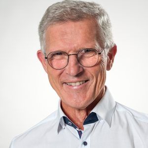 Porträt von Dr. med. Ludwig Ertl, lächelnd mit Brille in einem weißen Hemd