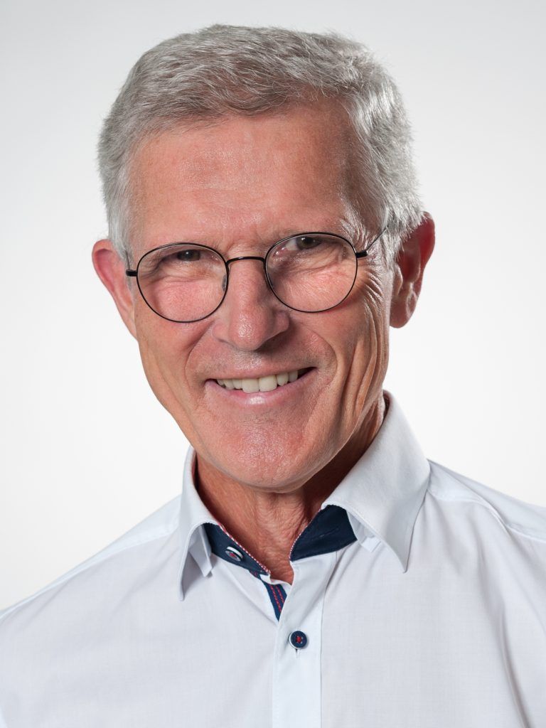 Porträt von Dr. med. Ludwig Ertl, lächelnd mit Brille in einem weißen Hemd